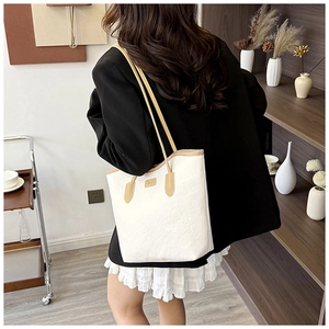 Detailed view of embossed leather tote bag with heart patterns and contrasting brown handles