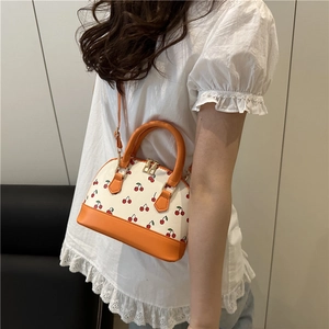 Fashionable white cherry shell bag with orange handles shown on a model for daily use