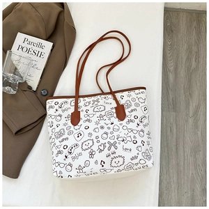 Detail of white canvas tote bag with black doodle art and brown leather handles