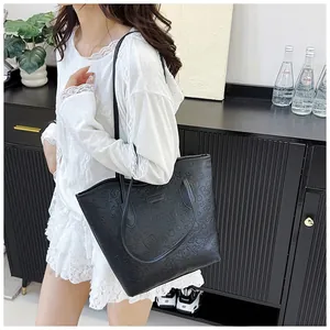 Detail view of large black tote bag with embossed patterns on smooth PU leather finish