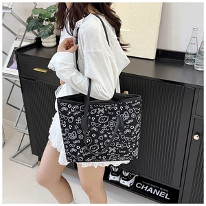 Detail of large capacity canvas tote bag featuring white graffiti print on black fabric
