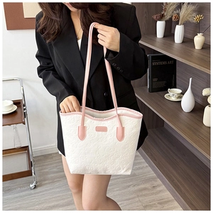 Detail of white tote bag with pink straps and intricate cartoon embossed patterns