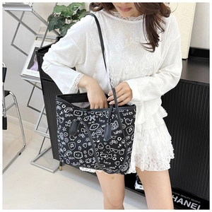Close-up of black tote bag featuring white hand-drawn graffiti and slim shoulder straps