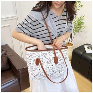 Close-up of casual graffiti canvas tote bag with brown leather handles on shoulder