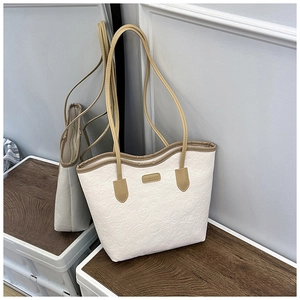 Detail view of white tote bag featuring embossed cartoon patterns and branded metal plate