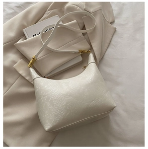 Detail of creamy white crescent shoulder bag featuring premium python skin texture and gold buckle