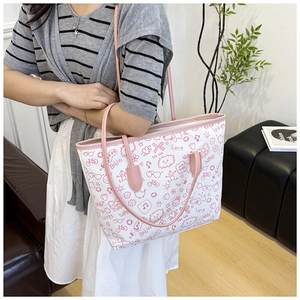 Detail view of large canvas tote bag with pink graffiti prints and leather straps