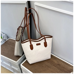 Detail of embossed cartoon patterns on a white faux leather tote bag with brown trim