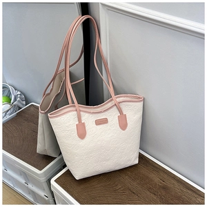 Detail of embossed heart and bow patterns on beige tote bag with pink accents