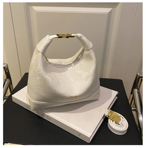 Detail of white snake-embossed leather handbag with gold metal clasp and adjustable strap
