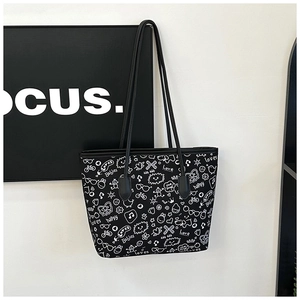 Detail of a black tote bag featuring white graffiti prints and stylish long shoulder straps