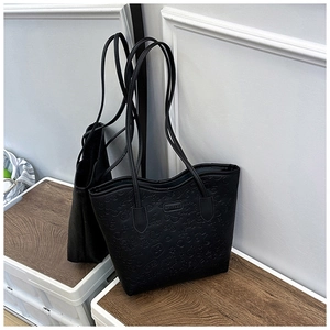 Detail of black tote bag with embossed cartoon patterns and slim leather shoulder straps
