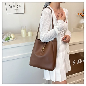 Detail of a dark brown leather bucket bag featuring a vintage gold metal hook clasp detail