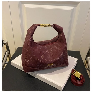 Detail of burgundy snakeskin texture on a crescent handbag with gold hardware