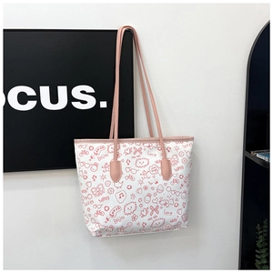 Detail of canvas tote bag featuring pink cartoon graffiti prints and leather straps