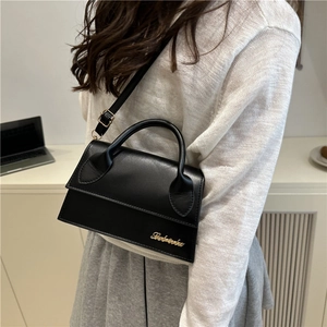 Minimalistische schwarze Trapez-Schultertasche mit goldfarbenem Logo in modernem Interieur