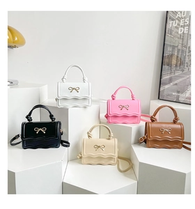 Close-up of matte leather shoulder bags in multiple colors with gold bow buckles