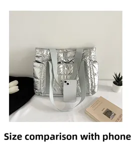Detail der silbernen Stepptasche im Größenvergleich zu einem Smartphone als Referenz