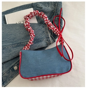 Detail of red checkered ruffled strap and denim fabric on stylish crossbody handbag