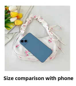 Floral handbag detail showing size comparison with a smartphone and ruched handle