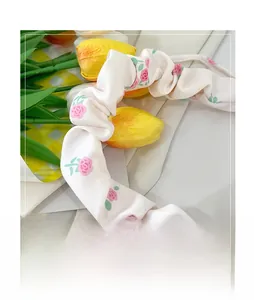 Close-up of pleated floral scarf handle wrap with pink roses on a white fabric base