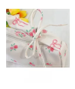 Detail of floral canvas bag showing pink rose prints, zipper and white bow decoration