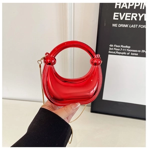 Detail of red crescent handbag with mirror finish, gold chain and round top handle