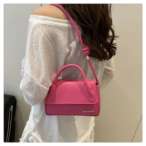 Vue détaillée du sac bandoulière rose avec logo doré et bandoulière nouée stylée