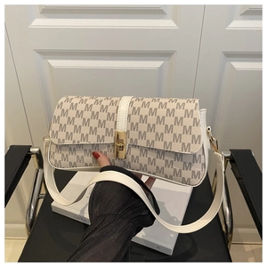 Gros plan sur le sac à bandoulière blanc crème avec fermoir doré et motif monogramme