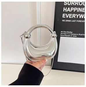 Close-up of silver mirror mini bag with round handle and thin metal chain strap