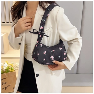 Detail of black floral shoulder bag with pink roses and bow tied on the satin strap