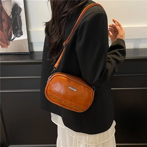 Braune Umhängetasche aus Leder mit Nieten und Metallplatte an einem Modestil