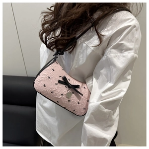 Close-up of pink seersucker bag with black bow tie prints and silver heart pendant