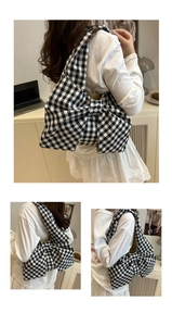 Detail of a black and white gingham tote bag featuring a large bow shape and wide strap