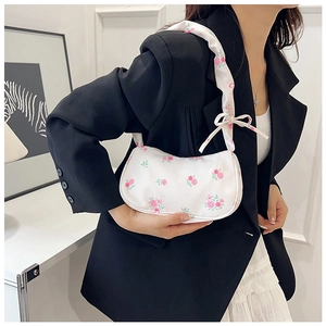 Detail of white floral shoulder bag with pink roses and ruffled bow strap on a model