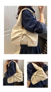 Detail of cream white tote bag with a large bow showing shoulder strap and fabric texture