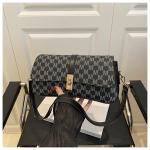 Détail d'un sac bandoulière rétro noir à monogramme M avec fermoir doré et bandoulière