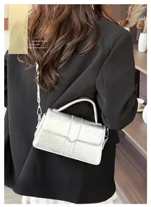 Detail of silver cracked texture flap handbag with crossbody strap on a black blazer