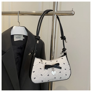 Close-up of seersucker textured shoulder bag with black bows and silver heart charm