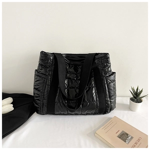 Detailaufnahme der schwarzen glänzenden Stepptasche mit großen Karos und Webgriffen