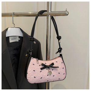 Detail of pink seersucker baguette bag with black bow patterns and silver heart pendant