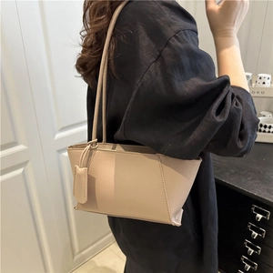 Minimalist beige tote bag with long shoulder strap and decorative tag for daily commute