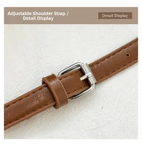 Detail of adjustable brown faux leather strap with silver buckle and fine stitching