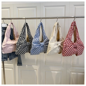Detailed row of five bow-knot shoulder bags in solid and plaid patterns against white background