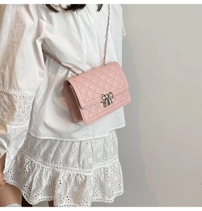 Sac bandoulière rose matelassé avec boucle nœud argenté porté sur robe blanche