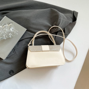Detail of cream handbag featuring sparkling glitter trim and minimalist top handle design