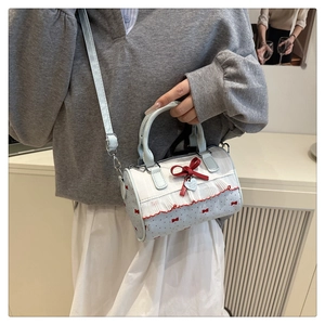Detail der blau-weißen Boston Bag mit roter Samtschleife und silbernem Herzanhänger