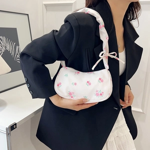 White floral shoulder bag with pink roses and bow details worn by a model in soft light