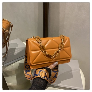 Close-up of orange textured small square bag with resin chain and patterned strap
