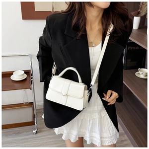 Close-up of a white leather crossbody bag with adjustable strap and top handle design
